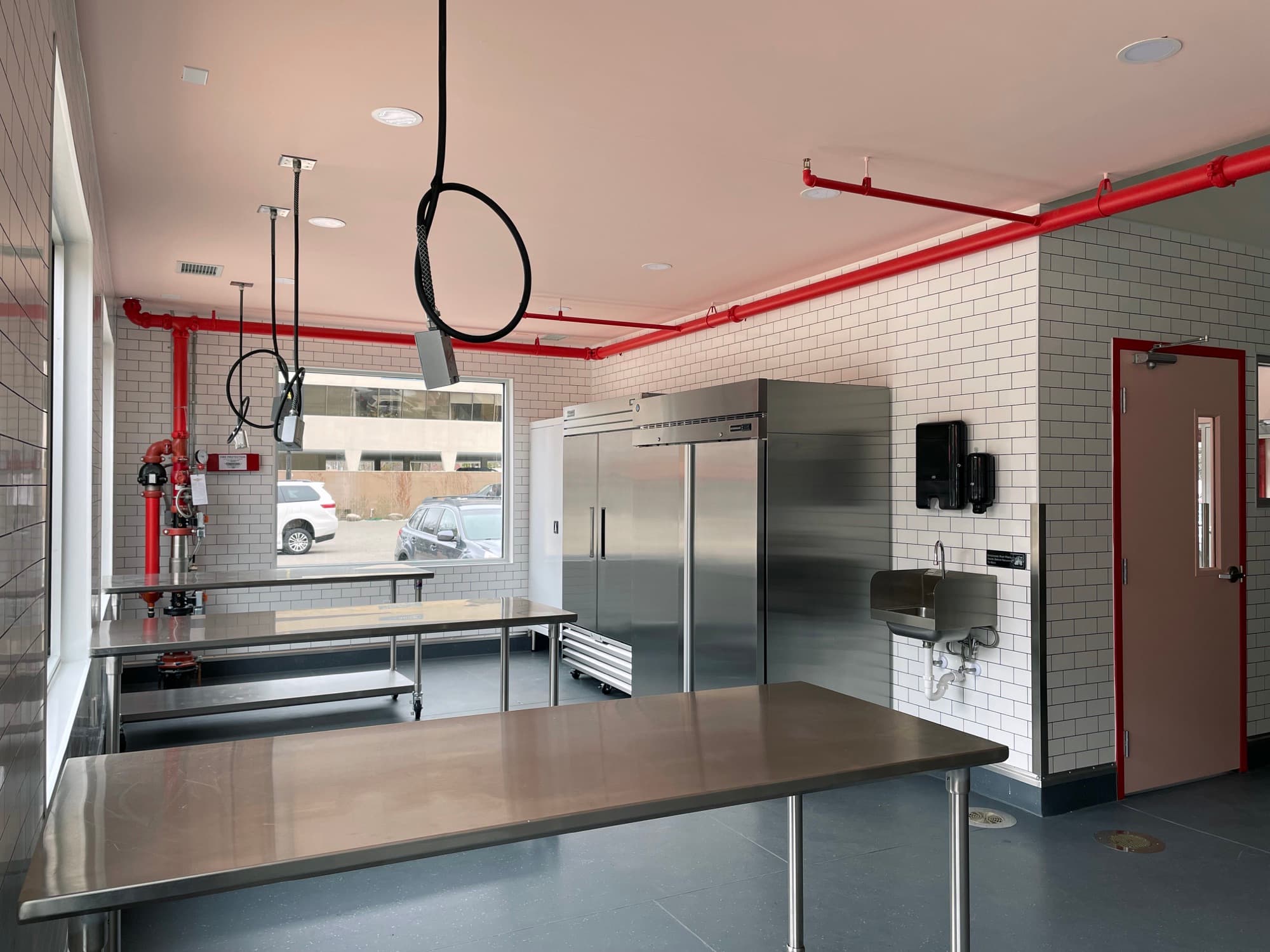 Teaching kitchen with stainless steel tables and a white tile wall