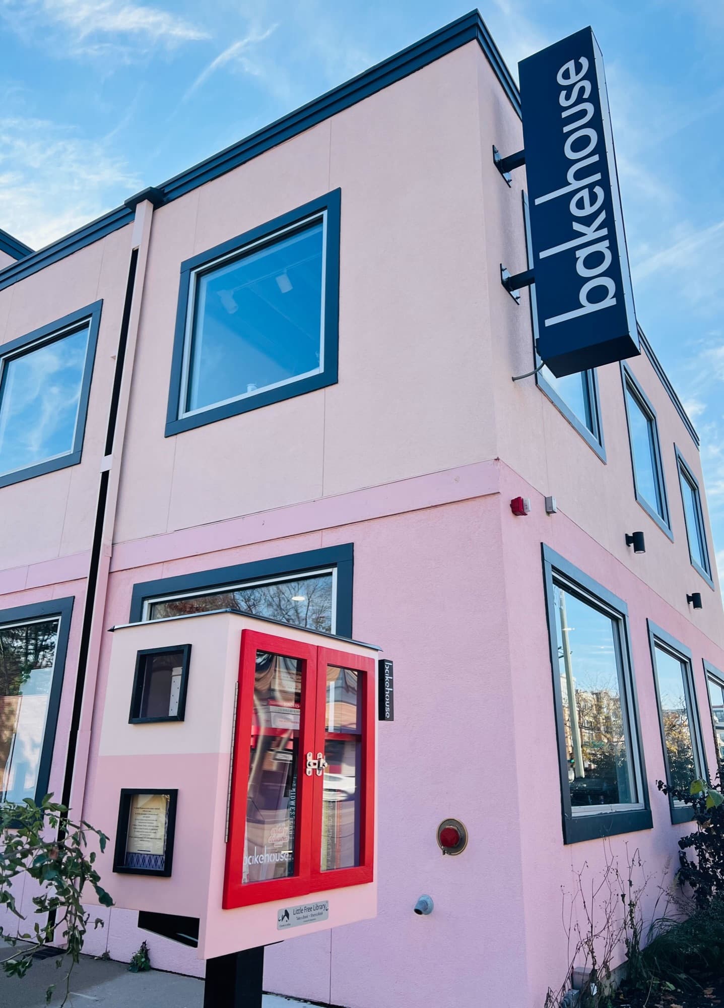 Corner of the bakehouse building with its vertical sign and a red cabinet at street level
