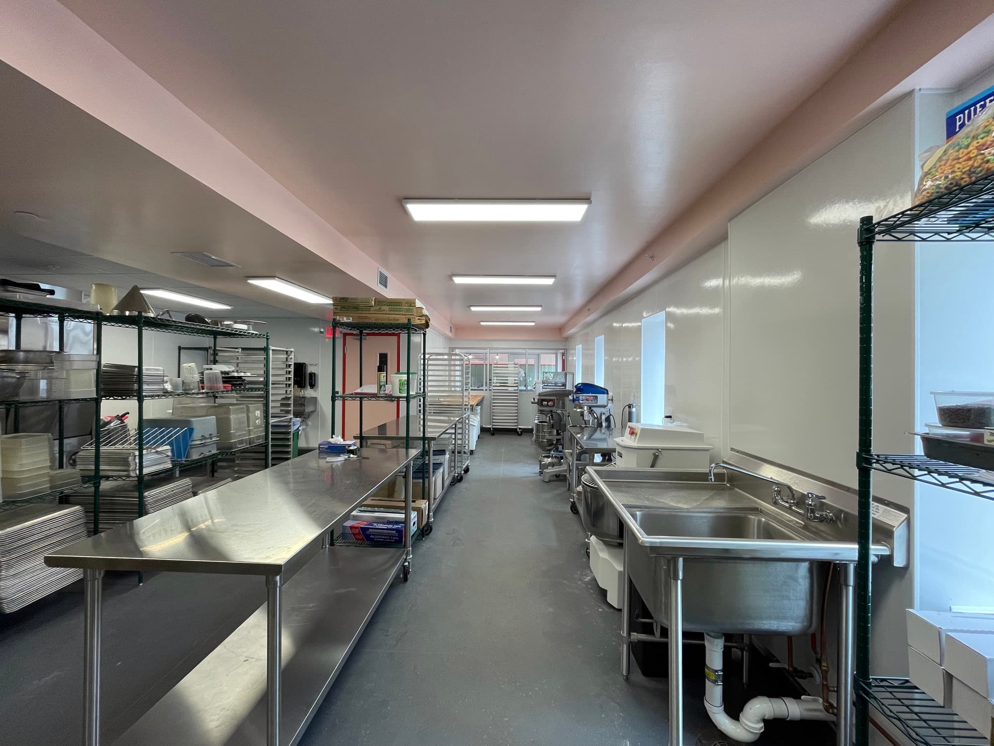Long commercial kitchen with stainless steel prep tables