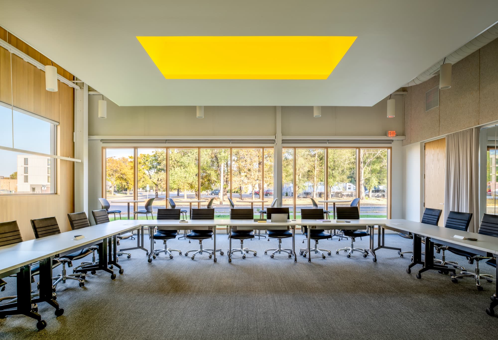 Conference room with long tables, windows and a yellow skylight