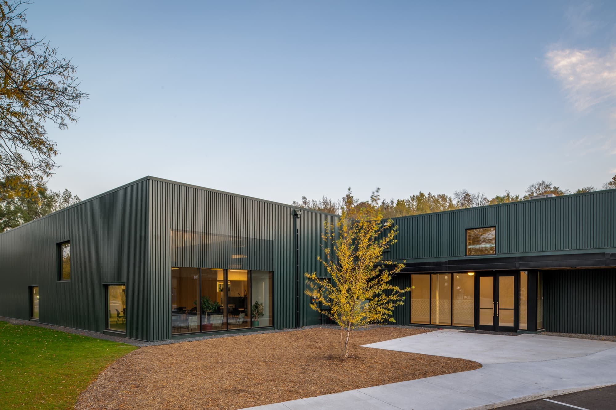 INFRA headquarters entrance seen from the lawn, with dark metal siding and wood-framed glazing