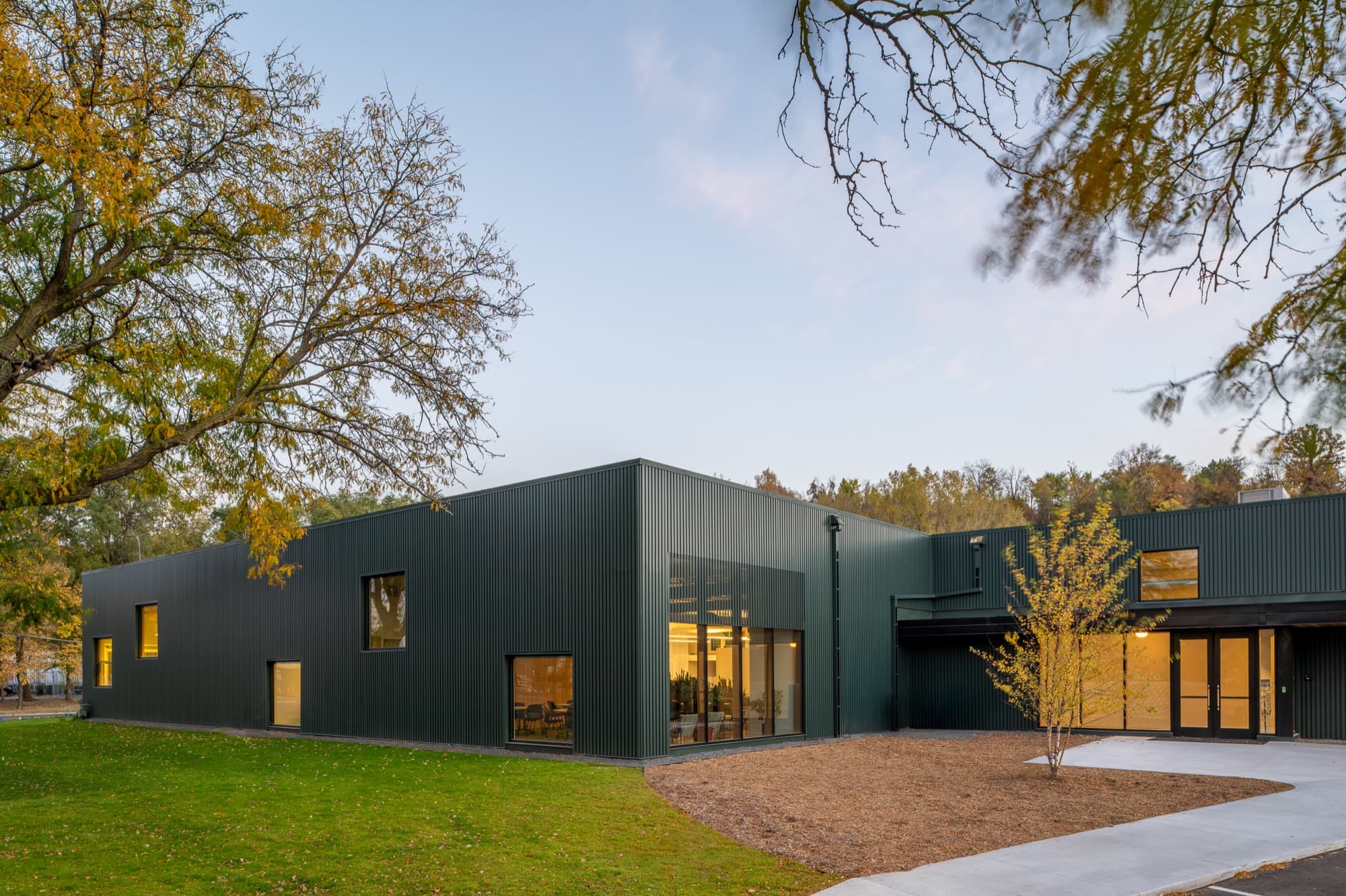 INFRA headquarters at dusk, a dark metal-clad building with warm light in the windows