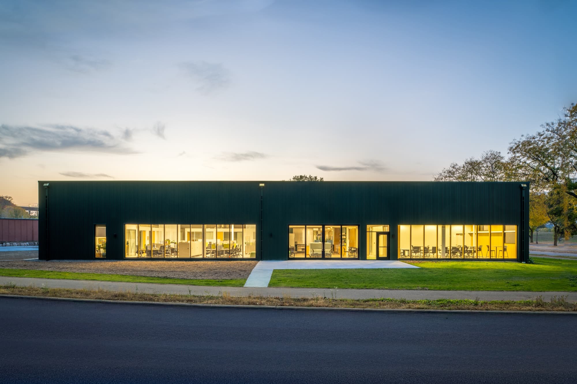Long facade of INFRA headquarters at dusk with lit windows