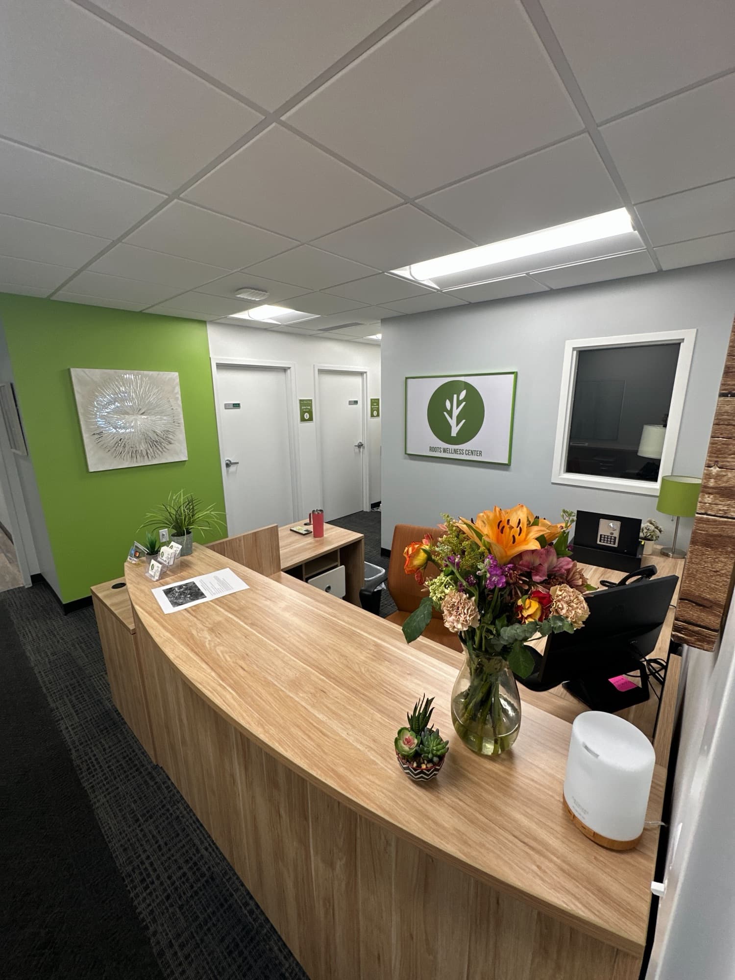 Reception desk with a curved wood counter and a vase of flowers