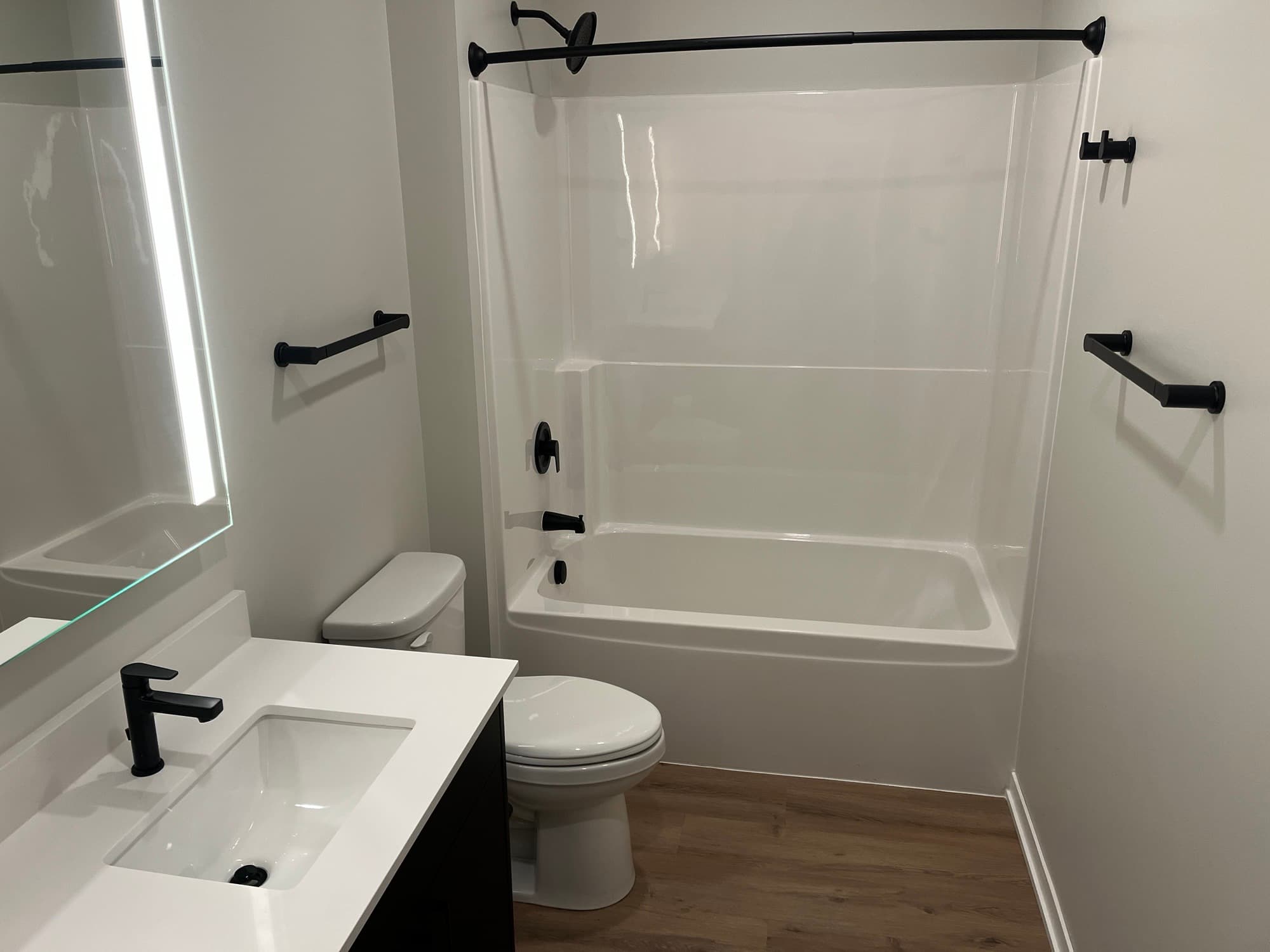 Updated apartment bathroom with a tub and black fixtures