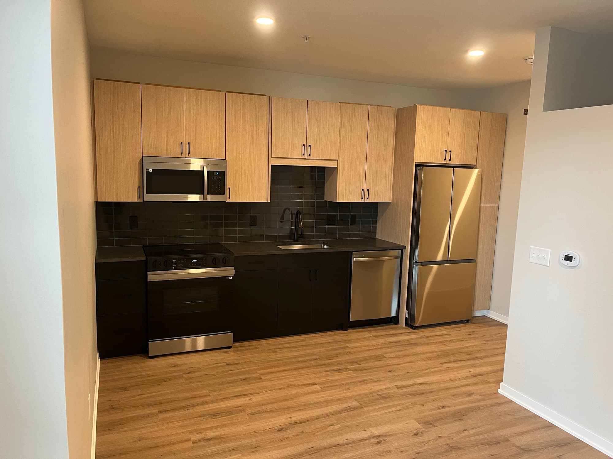 Apartment kitchen with light wood cabinets and stainless steel appliances
