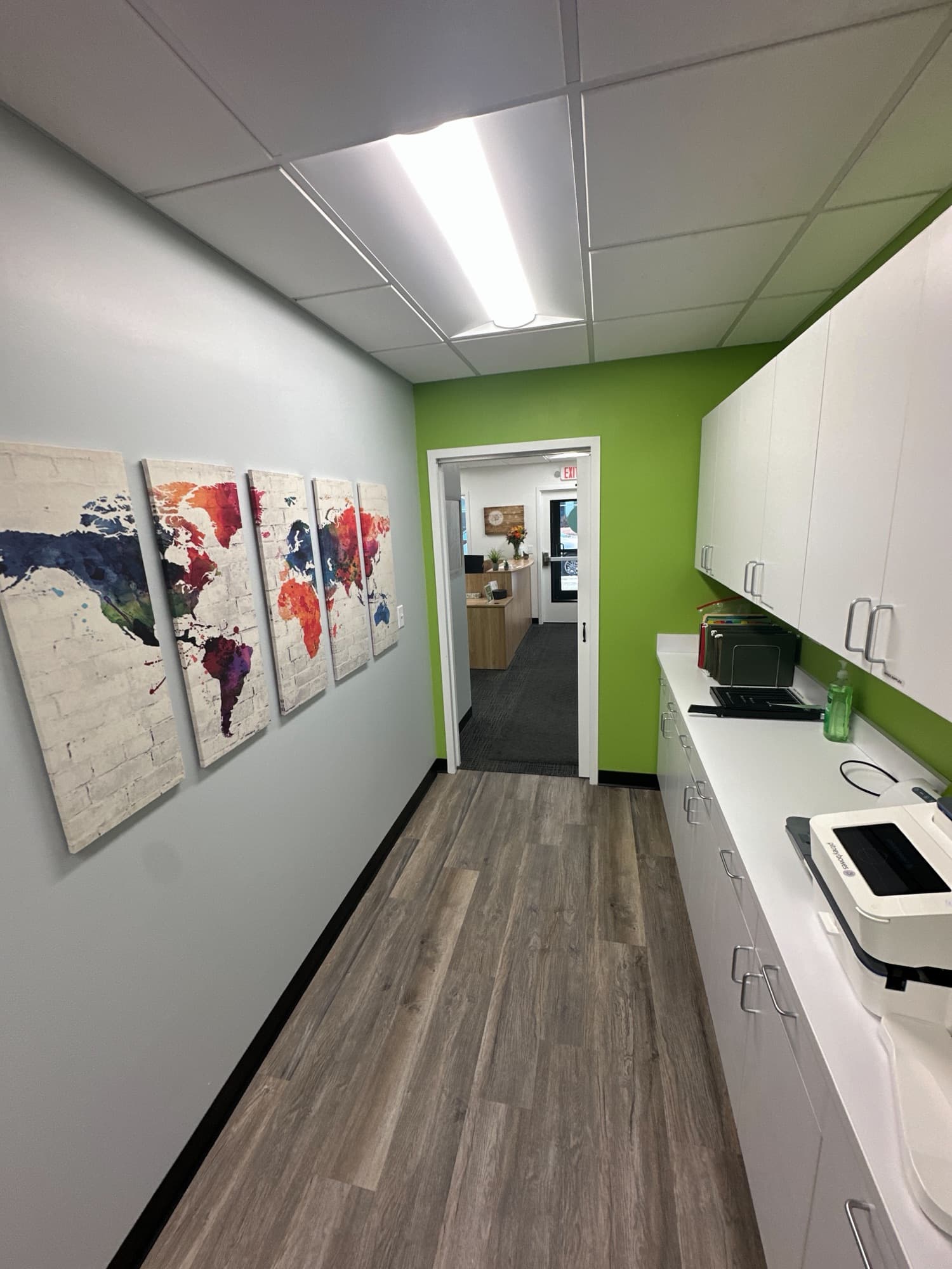 Hallway with kitchenette cabinets and framed map art